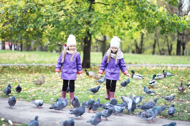 Caduta delle foglie nel parco. Bambini per una passeggiata nel parco autunnale. Famiglia. Autunno. Felicità.