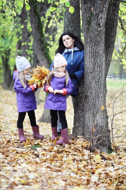 Caduta delle foglie nel parco. Bambini per una passeggiata nel parco autunnale. Famiglia. Autunno. Felicità.