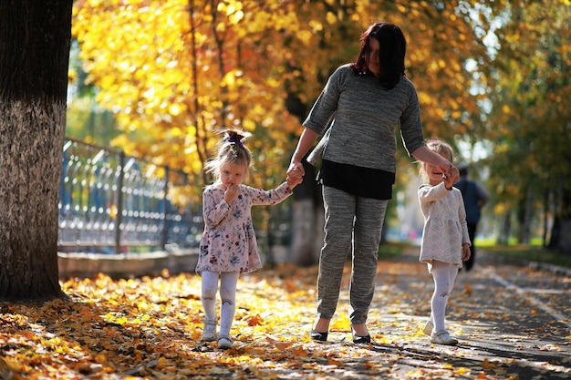 Caduta delle foglie nel parco. Bambini per una passeggiata nel parco autunnale. Famiglia. Autunno. Felicità.