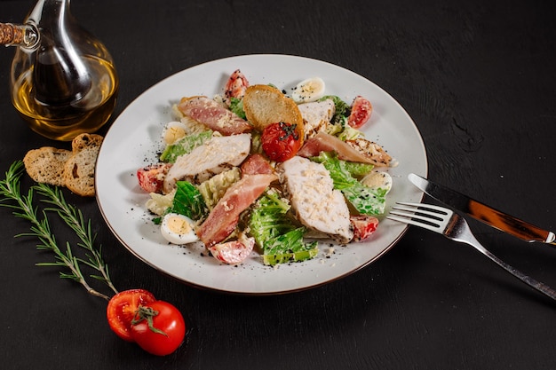 Caesar insalata fresca e gustosa con prosciutto e verdure su sfondo nero