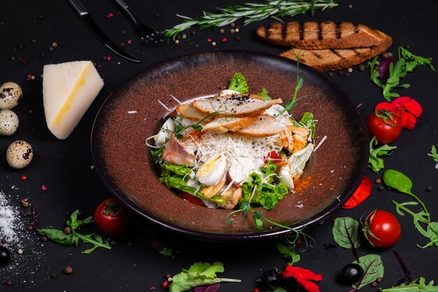 Caesar salad con filetto di pollo alla griglia e fette di pancetta, con pomodori e salsa Caesar.