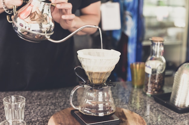 caffè a goccia, barista che versava acqua sul terreno di caffè con filtro