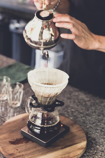 caffè a goccia, barista che versava acqua sul terreno di caffè con filtro