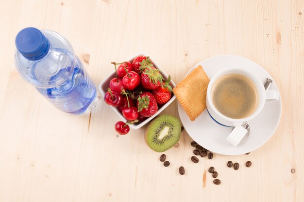 Caffè, acqua, torta e frutta sulla tavola di legno