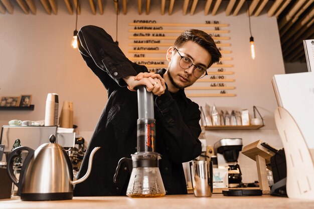 Caffè Aeropress Il barista sta spingendo l'aeropress per versare gocce di caffè attraverso l'aeropress nella caraffa Metodo alternativo di preparazione del caffè scandinavo