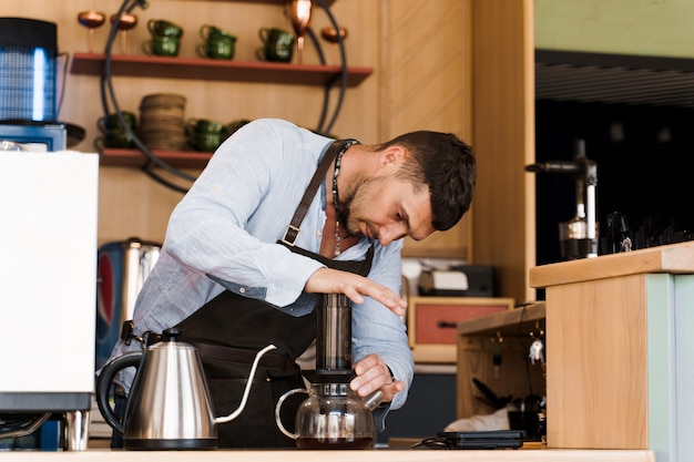 Caffè Aeropress: pressa da barista sul dispositivo e le gocce di caffè versano l'aeropress nella pentola