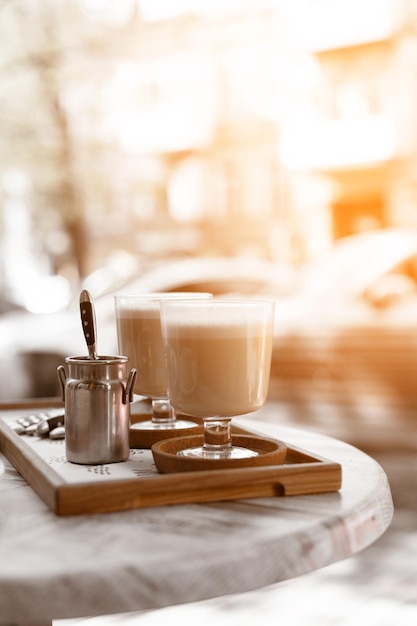 Caffè al latte aromatico in una tazza di vetro su un tavolino da caffè in un ristorante di strada. Gustose bevande mattutine.