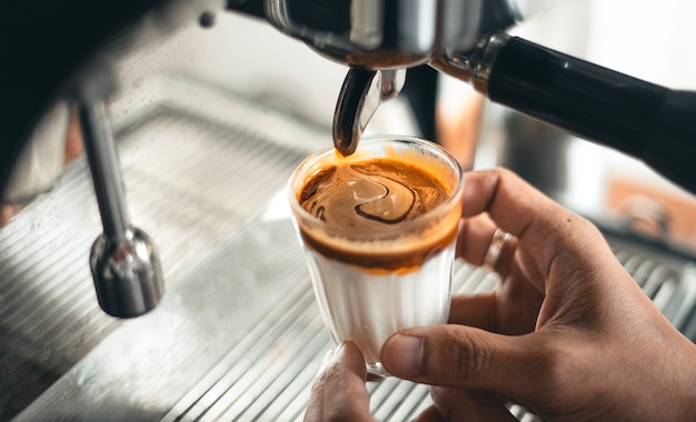 Caffè al latte, latte e caffè in un bicchiere dalla macchina