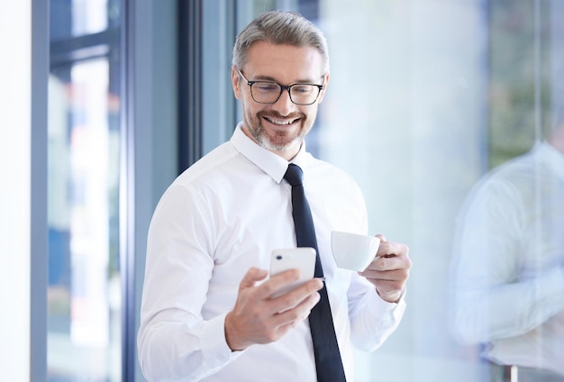 Caffè al telefono e uomo d'affari felice in ufficio che scorre sull'app mobile dei social media o su Internet Capo manager o capo professionista della tecnologia e di sesso maschile che legge il blog sul cellulare sul posto di lavoro