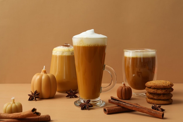 Caffè alla zucca in bicchieri spezie e candele su sfondo beige