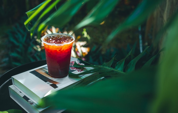 Caffè americano ghiacciato o caffè nero in vetro di plastica su un tavolo di legno in giardino