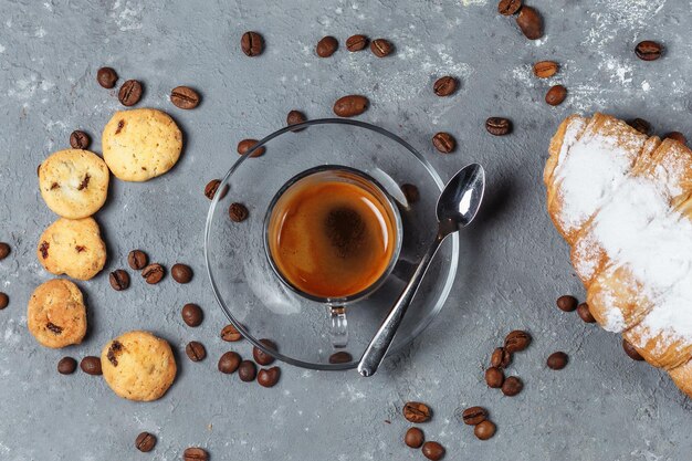 Caffè americano su fondo con croissant ai cereali e cannella