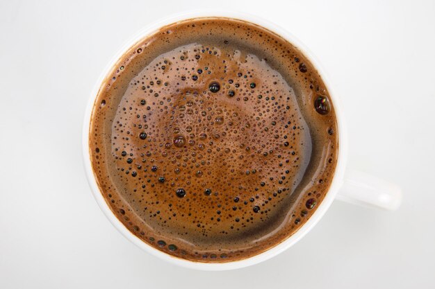 Caffè appena preparato in una tazza sul primo piano bianco del fondo