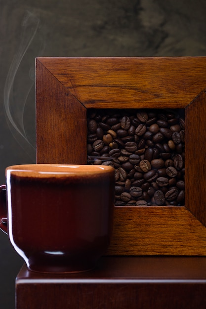Caffè aromatico fresco in una tazza di caffè e chicchi di caffè sul tavolo.