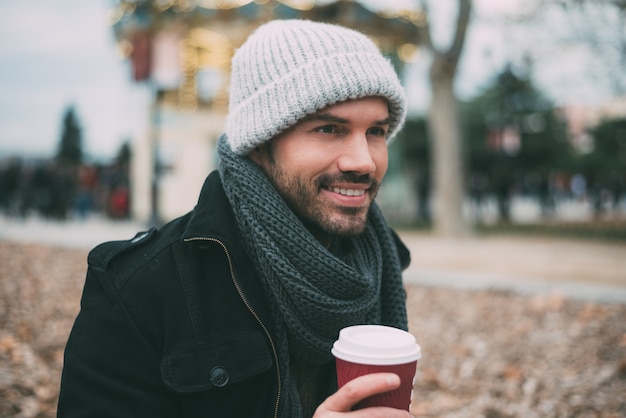 Caffè bevente del giovane uomo biondo vicino al palazzo reale in inverno