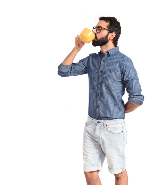 Caffè bevente del giovane uomo dei pantaloni a vita bassa sopra fondo bianco