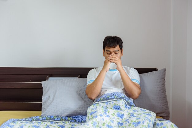 Caffè bevente dell&#39;uomo asiatico a tempo la mattina a casa