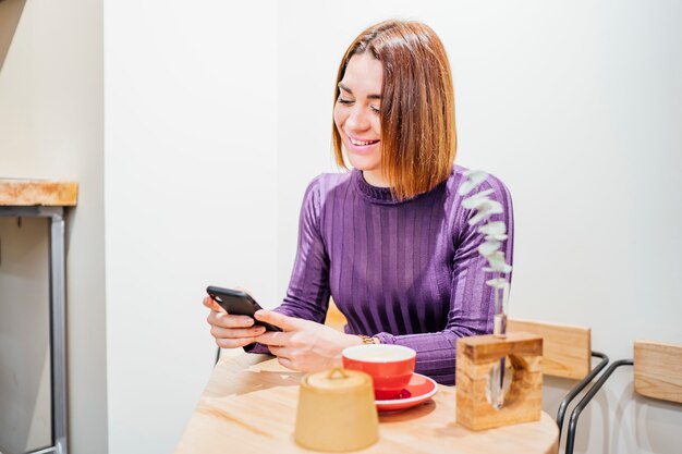 Caffè bevente della bella donna facendo uso del telefono cellulare