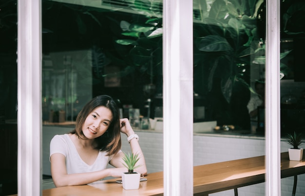 Caffè bevente della bella giovane donna che si siede dalla finestra nel caffè.