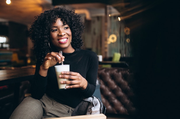 Caffè bevente della donna afroamericana in un caffè