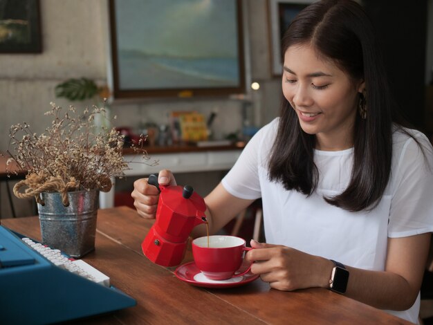 Caffè bevente della donna asiatica nel caffè della caffetteria