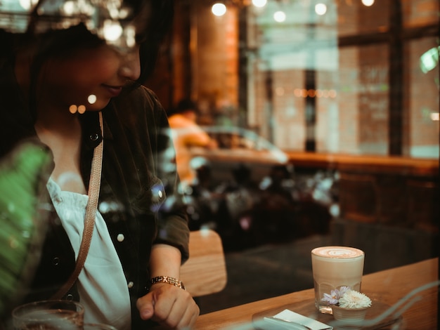 Caffè bevente della donna asiatica nel caffè della caffetteria