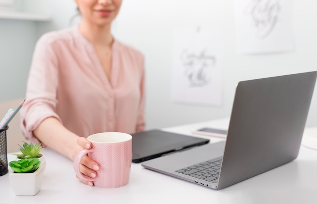 Caffè bevente della donna del primo piano mentre lavorando