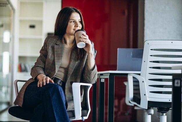 Caffè bevente della donna di affari in ufficio