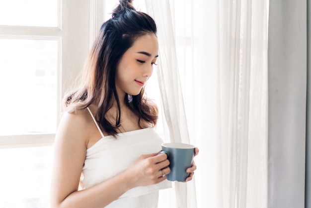 Caffè bevente della donna in camera da letto di mattina