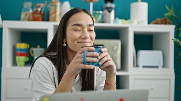 Caffè bevente della giovane bella donna ispanica che si siede sulla tavola alla sala da pranzo