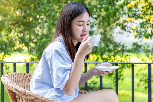 Caffè bevente della giovane donna al balcone.