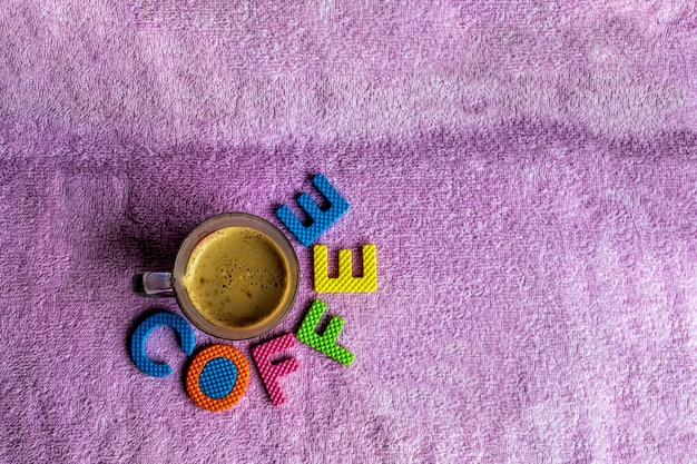 Caffè bianco in un bicchiere con uno sfondo di stoffa viola e materiale di sughero colorato