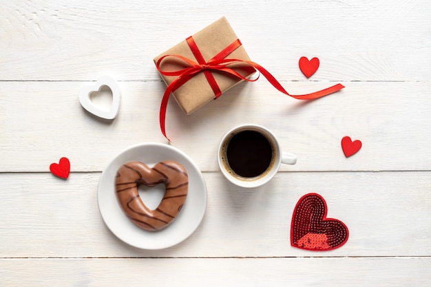 Caffè, biscotto al cioccolato a forma di cuore, confezione regalo sulla vista dall'alto del tavolo in legno bianco