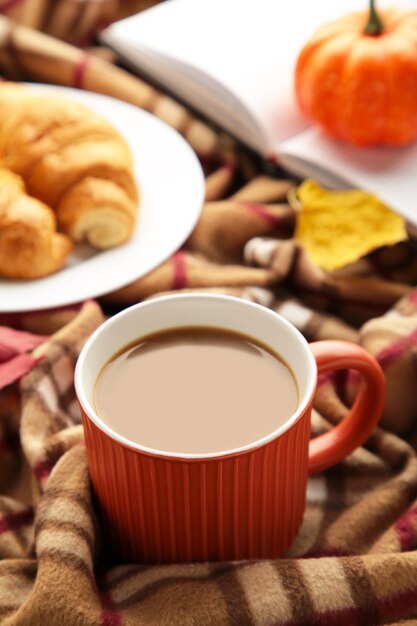 Caffè caldo con croissant e foglie d'autunno su plaid - concetto di relax stagionale. Foto verticale