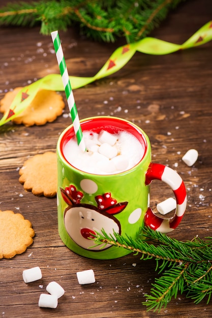 Caffè caldo con marshmallow e biscotti allo zenzero su fondo rustico in legno. Carta natale