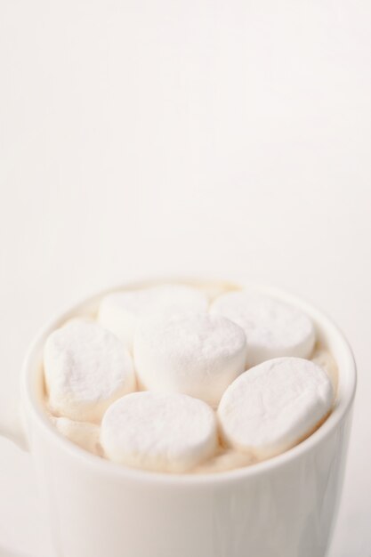 Caffè caldo con marshmallow in una tazza bianca sul tavolo. Coltura verticale