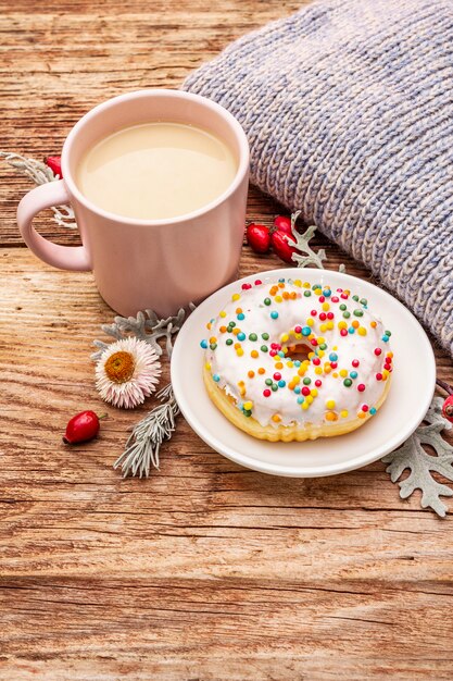 Caffè caldo con una ciambella. Bevanda autunnale per un buon umore con plaid, rosa canina, foglie e fiori freschi.