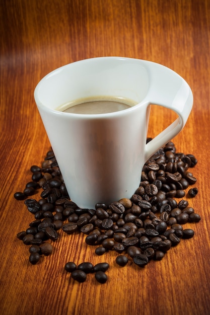 Caffè caldo e chicchi di caffè su uno sfondo di legno.