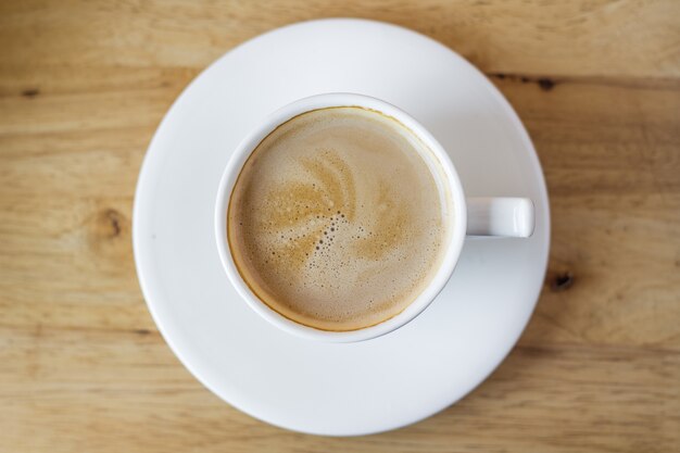 caffè caldo in tazza bianca sul tavolo con chicchi di caffè