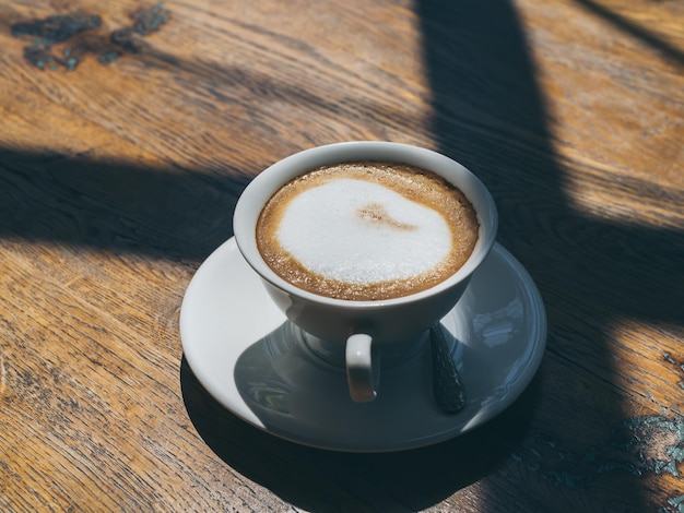 Caffè caldo in tazza di ceramica bianca rotonda sul fondo della tavola di legno