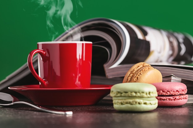Caffè caldo in tazza rossa, riviste e biscotti.