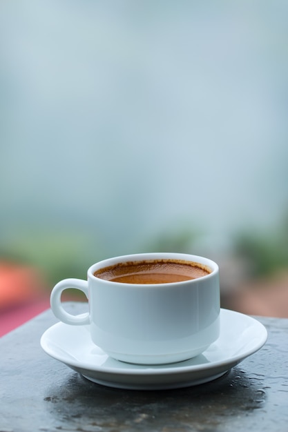 Caffè caldo in una tazza bianca sul tavolo.