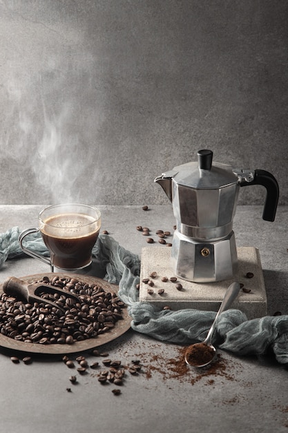 Caffè caldo in una tazza di vetro e chicchi di caffè su uno sfondo chiaro. Formato verticale.