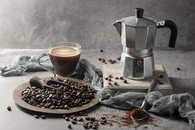 Caffè caldo in una tazza di vetro e chicchi di caffè su uno sfondo chiaro.