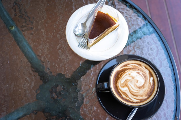 Caffè caldo latte con schiuma di latte arte latte in tazza tazza e torta al cioccolato fatta in casa sulla scrivania in legno sulla vista dall'alto come colazione in una caffetteria presso il concetto di lavoro aziendale cafeduring