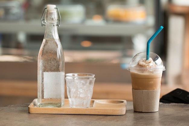 Caffè con ghiaccio capucino frape tazza di bevande sulla scrivania in legno con negozio di caffè sfocato