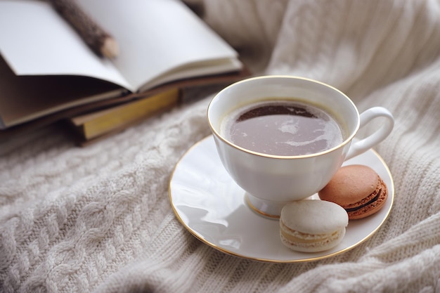 Caffè con il primo piano dei macarons sui precedenti di un taccuino con una matita