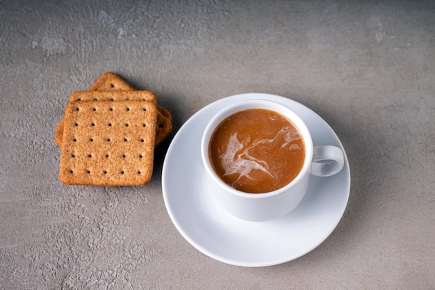 Caffè con latte in uno spazio della copia dei biscotti della tazza di caffè bianco