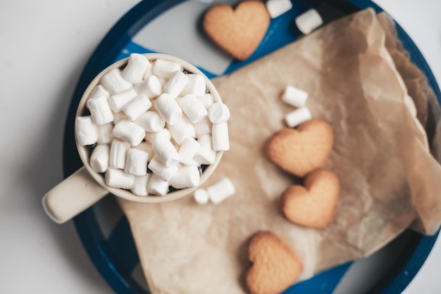 Caffè con marshmallow e biscotti a forma di cuore su un vassoio blu rotondo Appuntamento a San Valentino Set carino e dolce per San Valentino