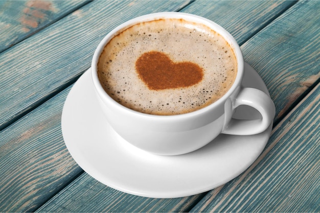 Caffè con schiuma a forma di cuore su fondo in legno